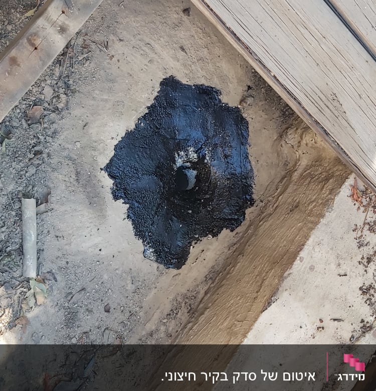 חומר איטום שחור סביב צינור בבסיס עץ